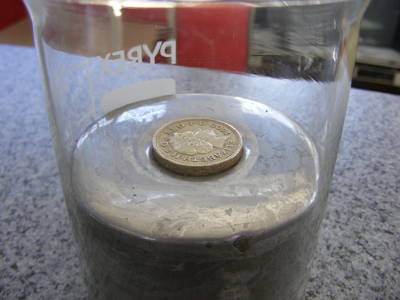 A coin floating on mercury. Buoyancy depends on the density of the fluid, and mercury is dense enough to float metals that sink in water.