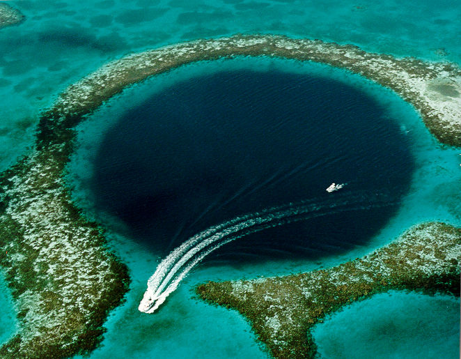 The Great Blue Hole, a vast circular marine sinkhole off the coast of Belize, plunging into the depths of the reef. A wonder of the country's barrier reef, it is among the most celebrated dive sites in the world.