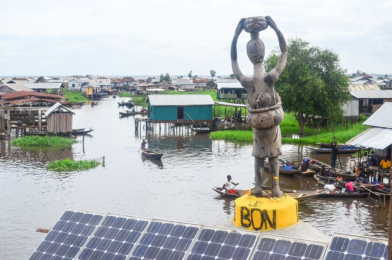 Ganvie, the stilt village on Lake Nokoue. Tradition holds it was founded by people escaping Dahomean slave raiders, who were forbidden by religious injunction to pursue anyone onto the water, and tens of thousands of people still live above the lake and travel by pirogue.
