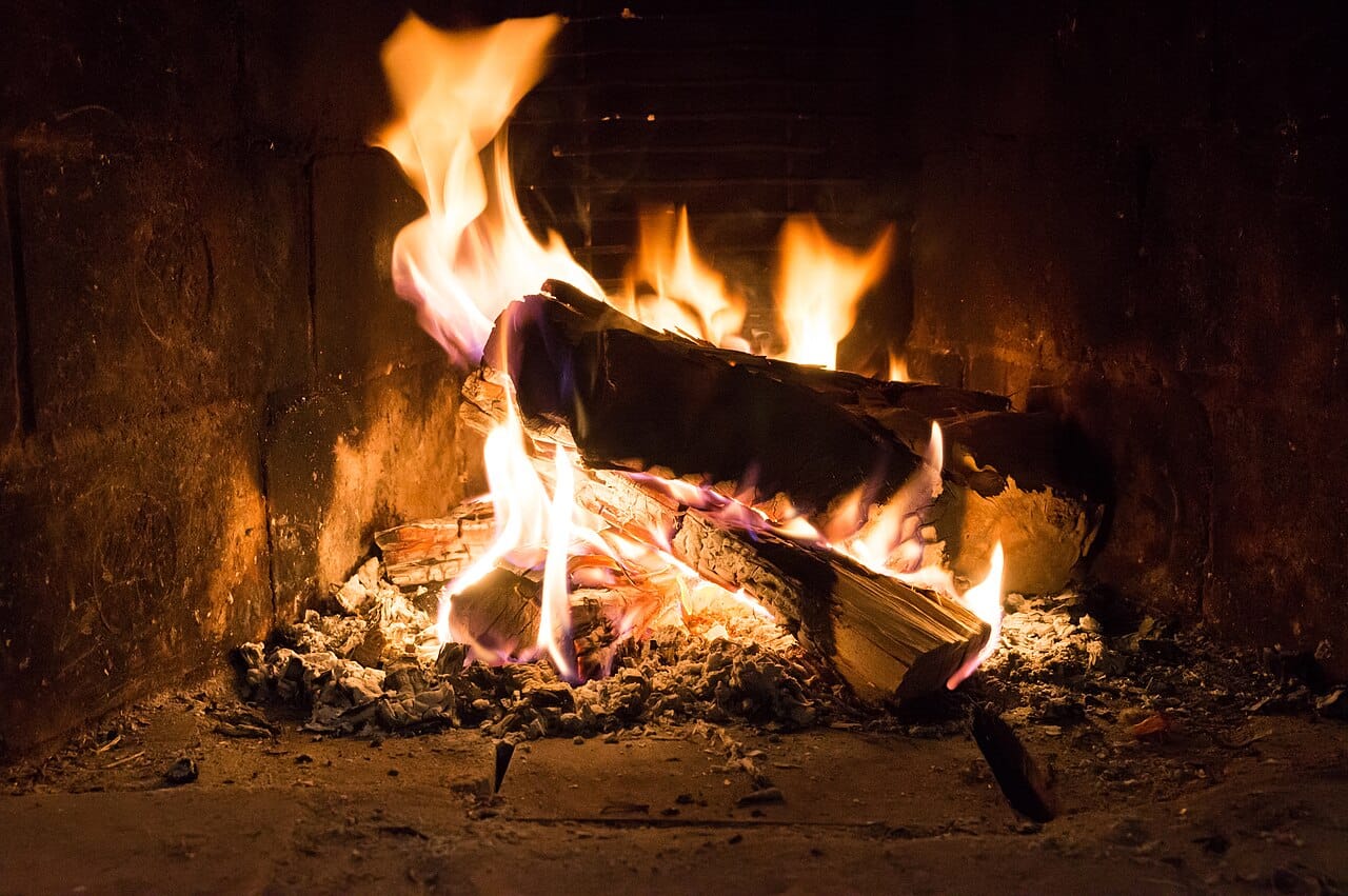 A wood fire. The visible flame is a region of gas hot enough to emit light, and the solid fuel is not burning directly but releasing gases that burn above it.