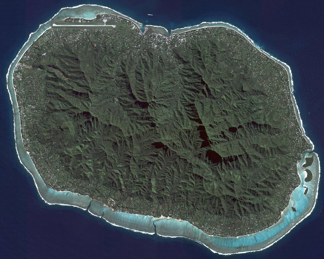 Rarotonga from the air. The volcanic interior rises to 652 metres and has never been settled, so the entire population lives on the narrow coastal plain between the mountains and the reef.