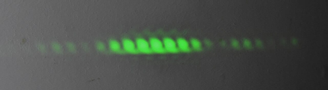 Young's arrangement. Light passing through two narrow slits produces alternating bright and dark bands, which particles travelling in straight lines cannot explain.