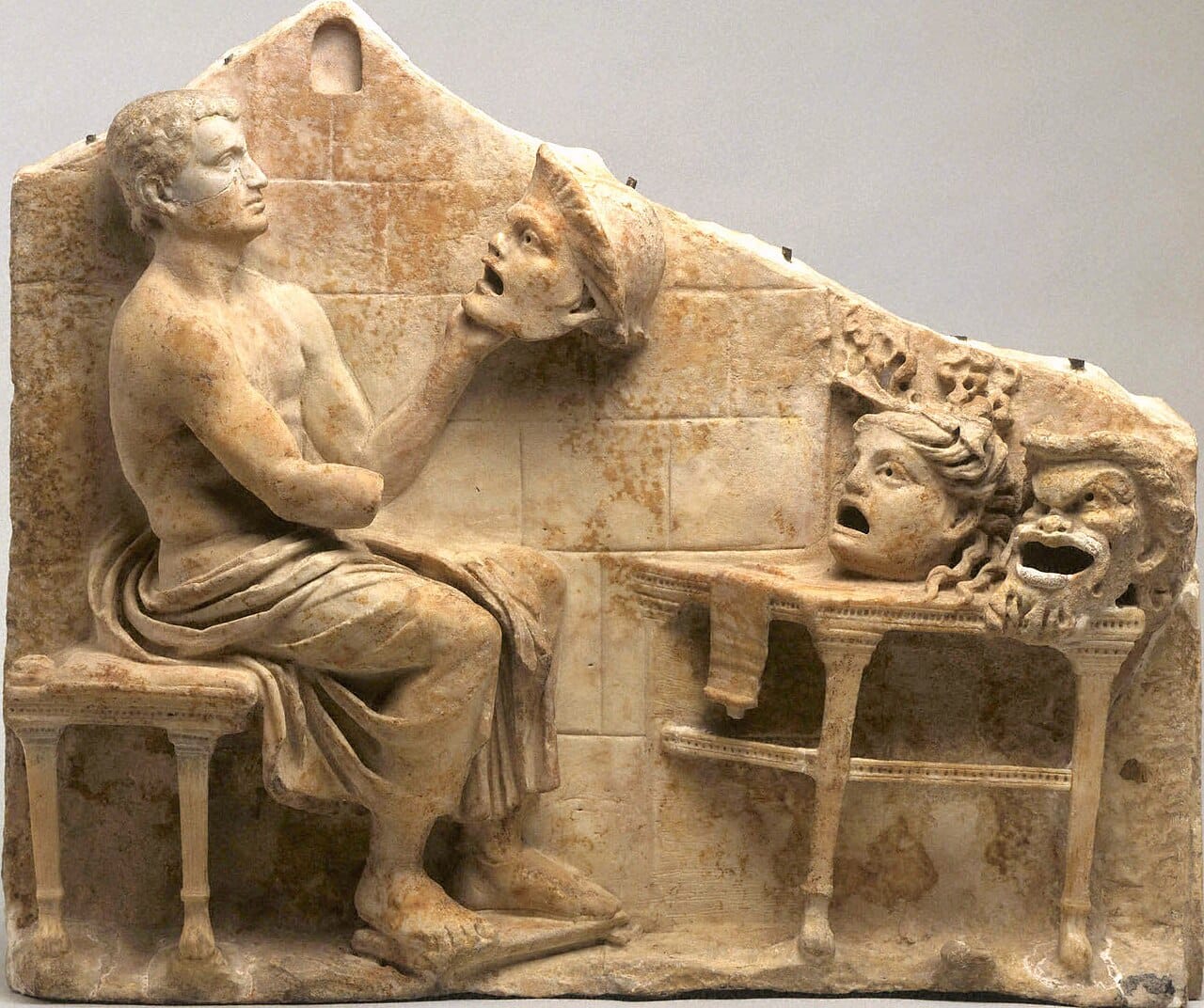 A relief showing the playwright Menander with comic masks. Masks allowed a small cast to play many roles and identified character type immediately to a large audience.