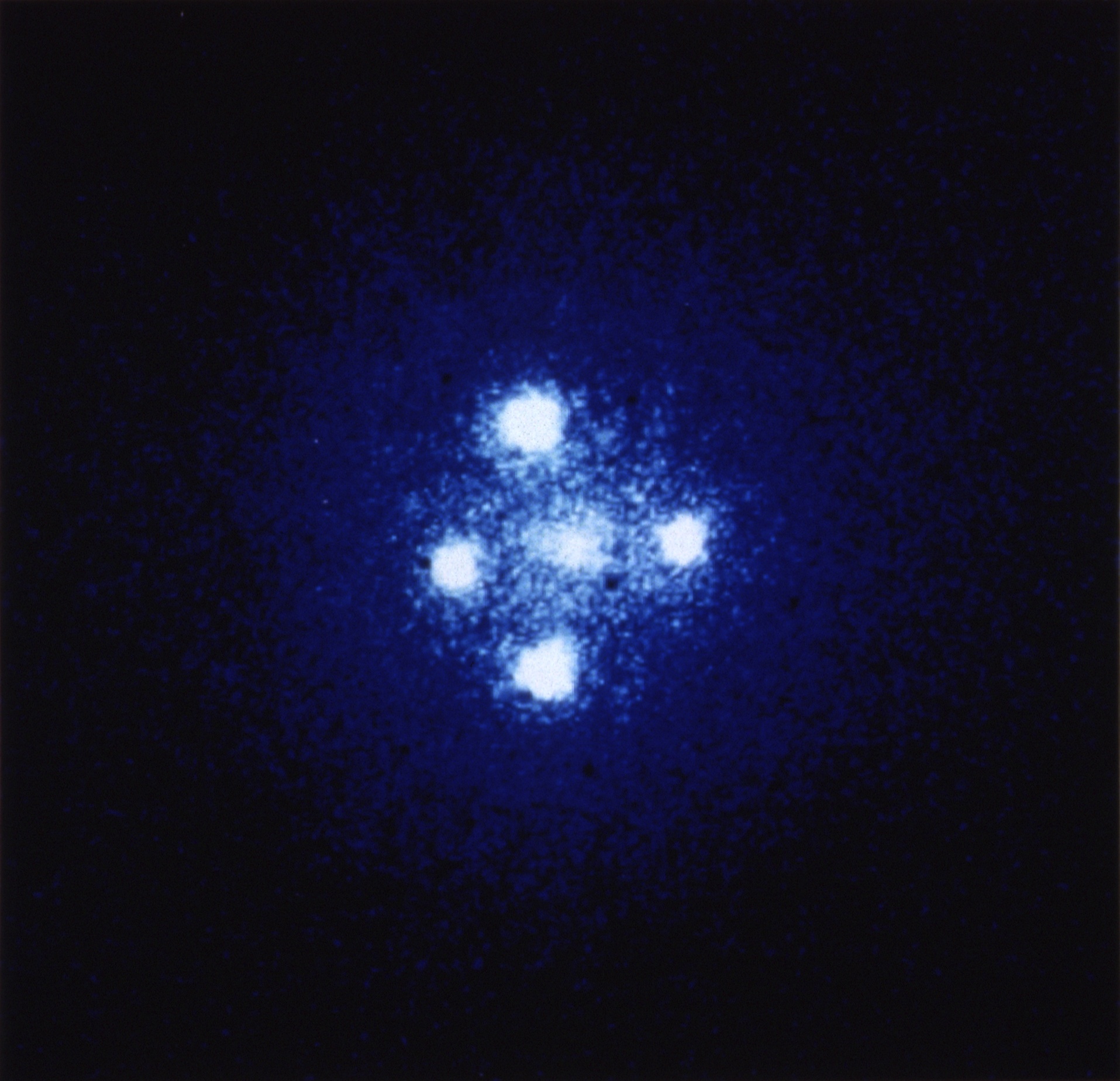 A formation where one distant object appears as several images around a galaxy.