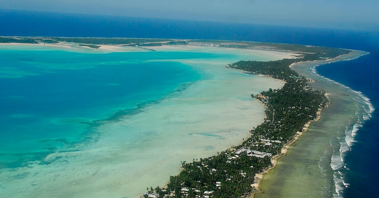 South Tarawa, the crowded capital atoll of Kiribati, seen from the air. A large share of the nation is packed onto this thin, low ribbon of coral, whose exposure to the rising ocean makes it a symbol of the climate threat facing low-lying island states.