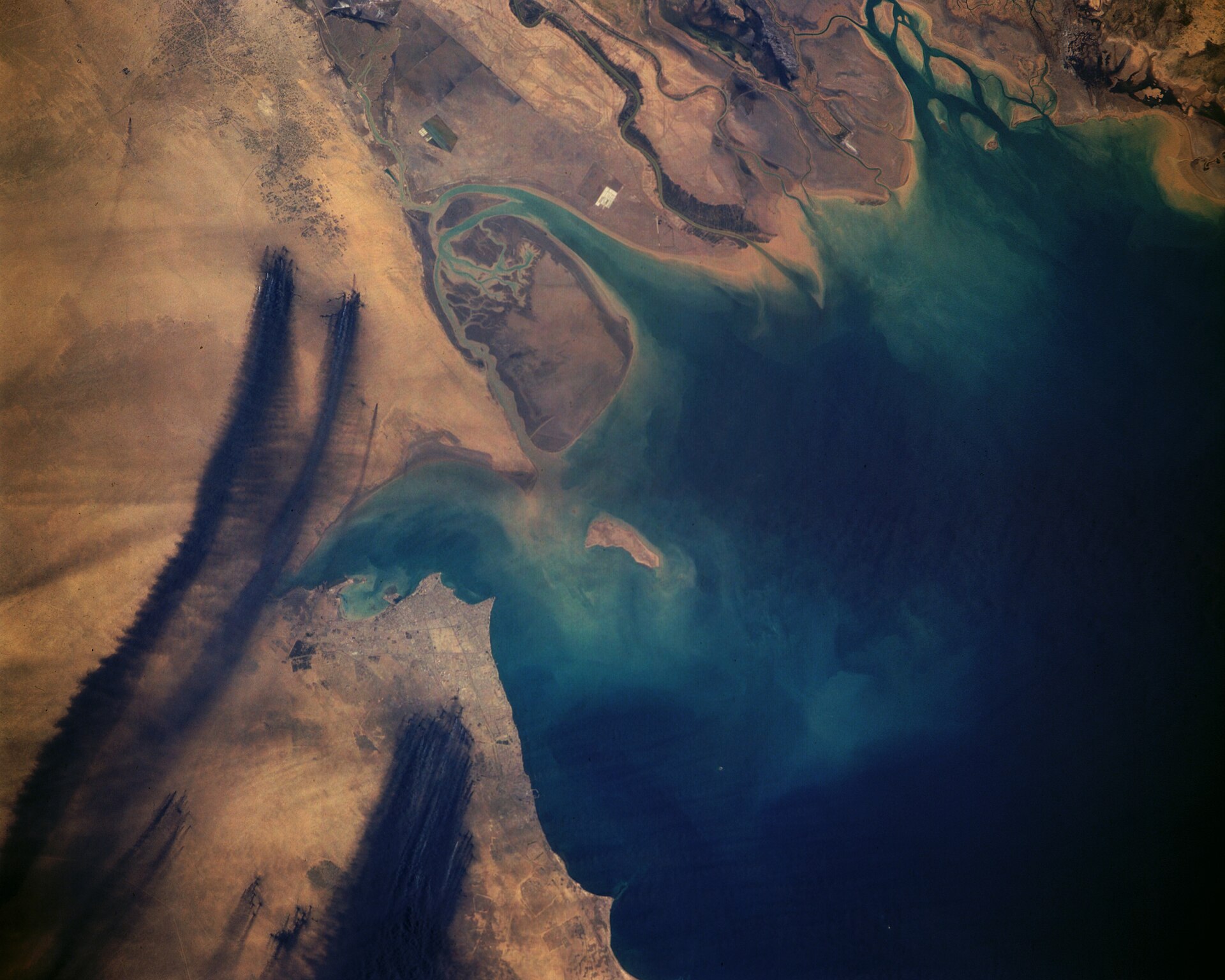 Smoke pouring from Kuwaiti oil wells set alight by retreating Iraqi forces in 1991, seen from space. The fires, part of the devastation of the Gulf War, took months to extinguish and caused lasting environmental harm.