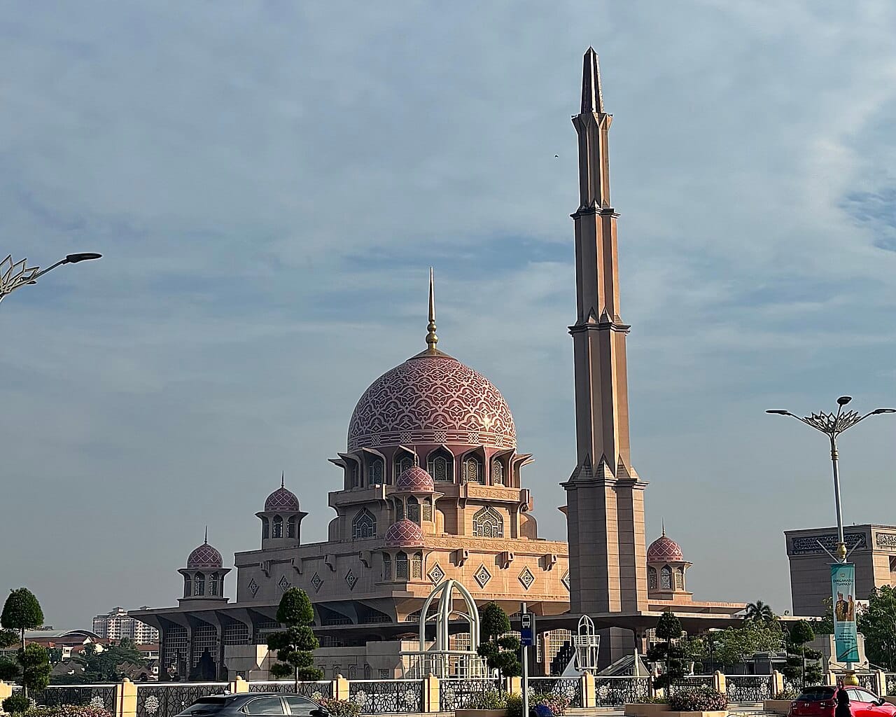 The Putra Mosque in Putrajaya, the modern administrative capital, its rose-tinted dome rising beside a lake. Islam is the official religion of Malaysia and central to the Malay majority, one thread in the country's rich religious tapestry.