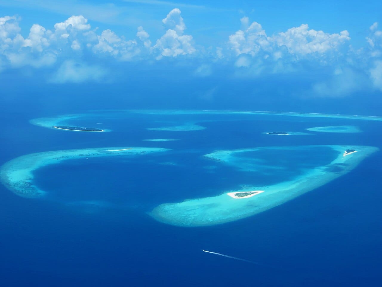 An aerial view of Maldivian atolls, rings of coral reef and low sandy islands scattered across the Indian Ocean. With most of its land barely a metre above the sea, the Maldives is the lowest-lying country on Earth.