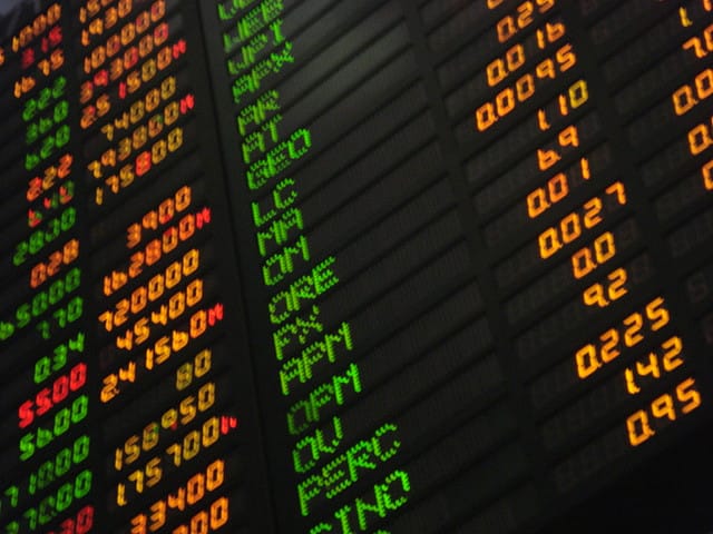 A stock exchange board. The theory's most consequential practical descendant is the argument for holding the whole market cheaply rather than selecting within it.