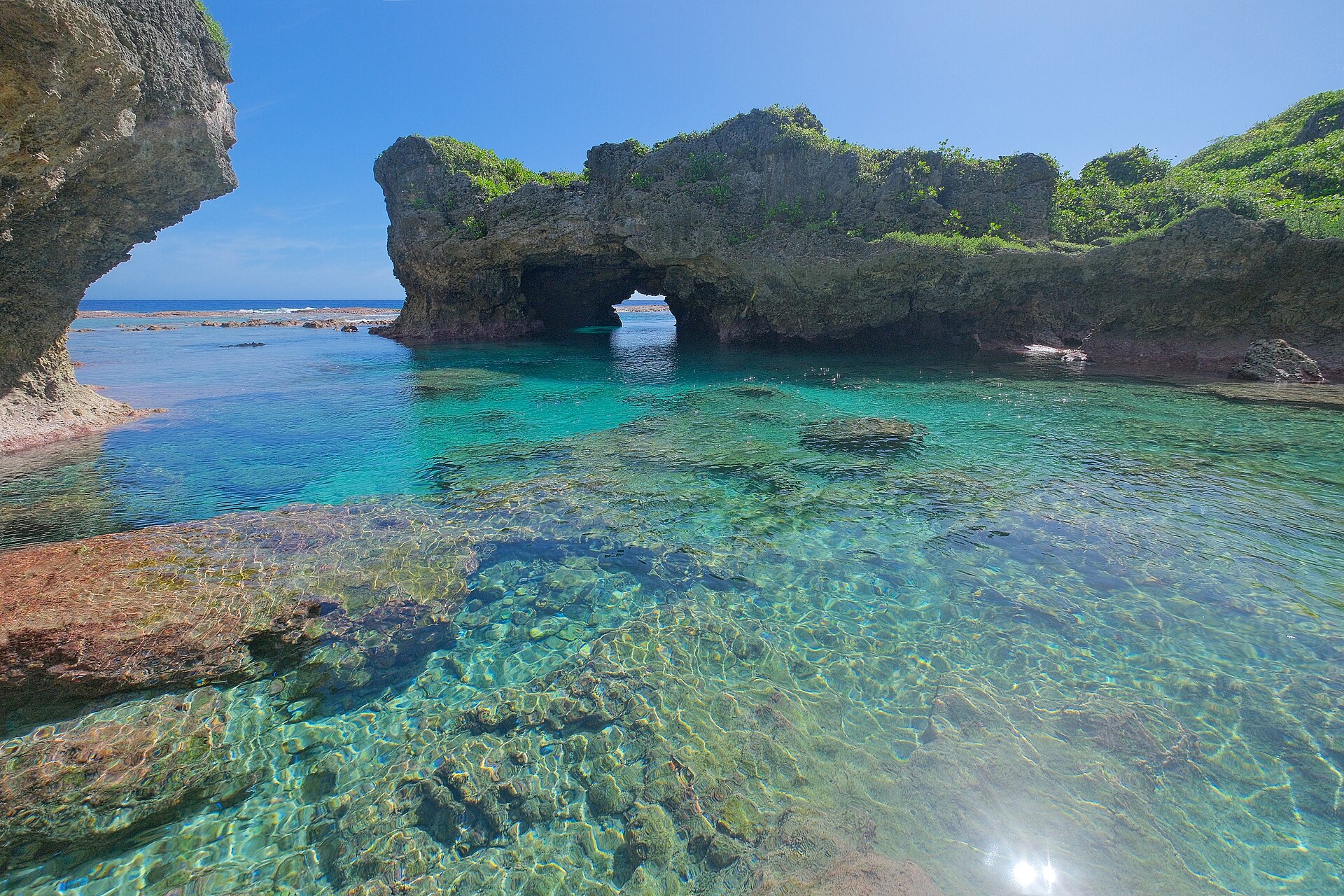 A natural stone arch on the rugged limestone coast of Niue, one of the island's dramatic coastal features. Credit: Pseudopanax at English Wikipedia (Public domain).