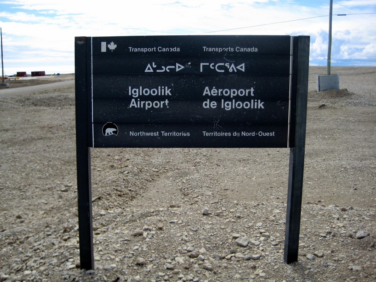 An airport sign in Igloolik written in Inuktitut syllabics and the Latin alphabet. Inuktitut is spoken by most people in Nunavut and holds official status, one of the strongest positions of any Indigenous language in the Americas.