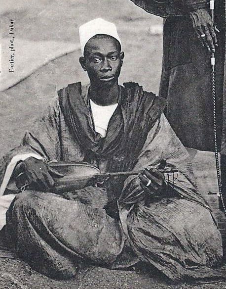 A West African griot with a ruler. Griots are professional custodians of genealogy, history and praise poetry, holding an office with defined obligations rather than performing informally.