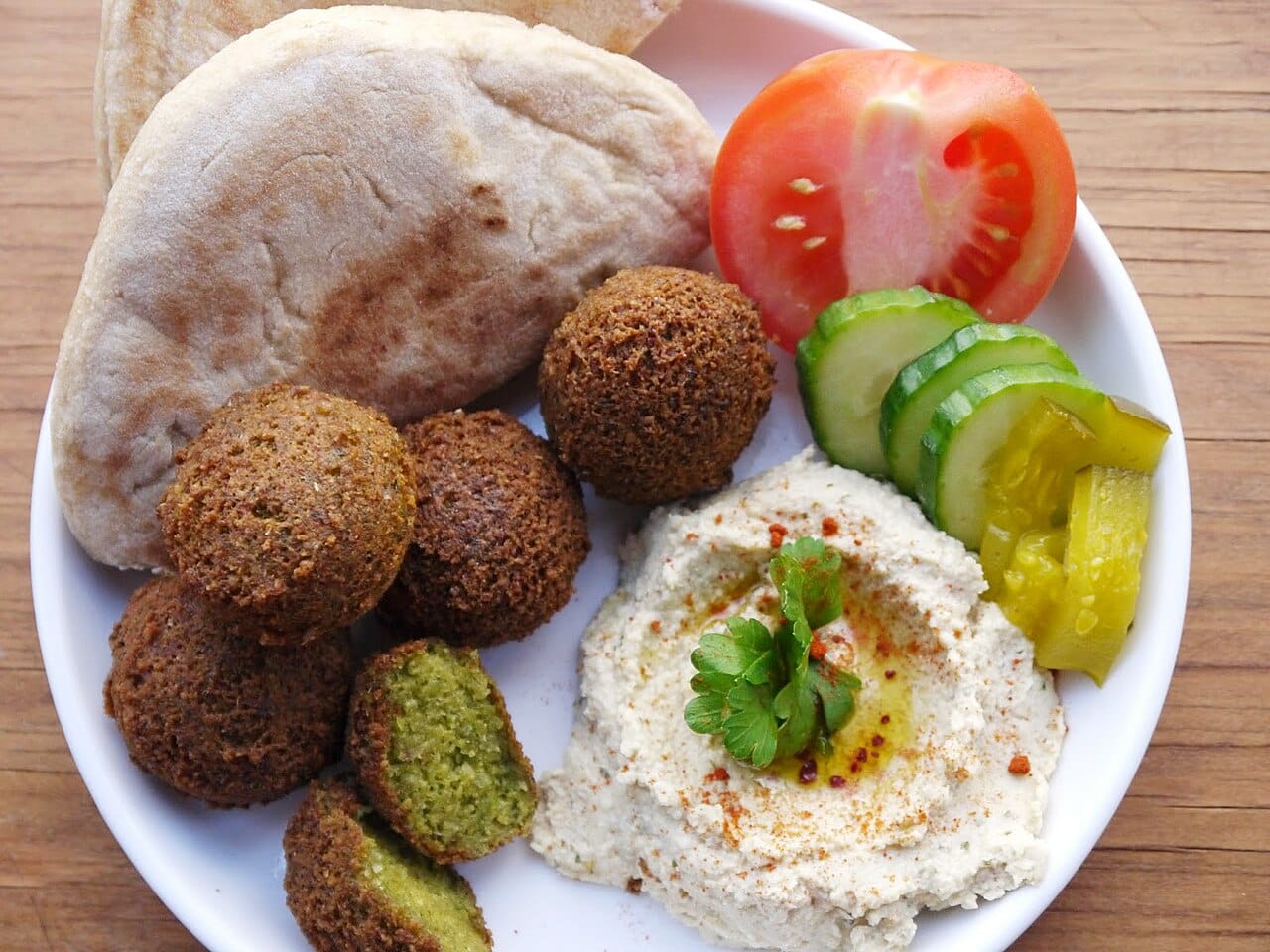 A Palestinian breakfast of falafel, hummus, and vegetables. Olive oil, wheat, pulses, and za'atar are the foundation of a cuisine shared across the eastern Mediterranean and claimed with some feeling by several national traditions at once.