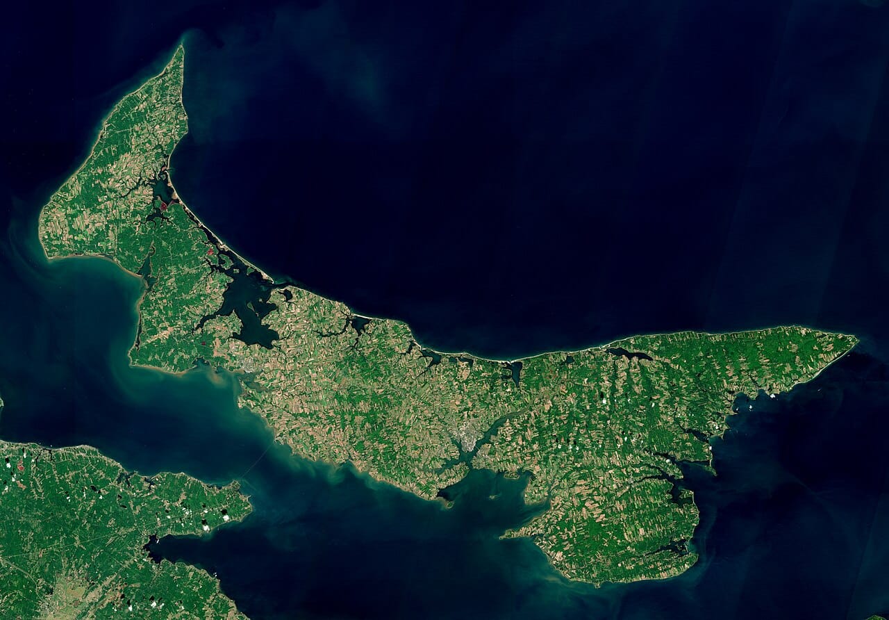 A satellite view of Prince Edward Island, showing its long crescent shape in the Gulf of St Lawrence. The smallest province, it is a low, gentle island of farmland and beaches.