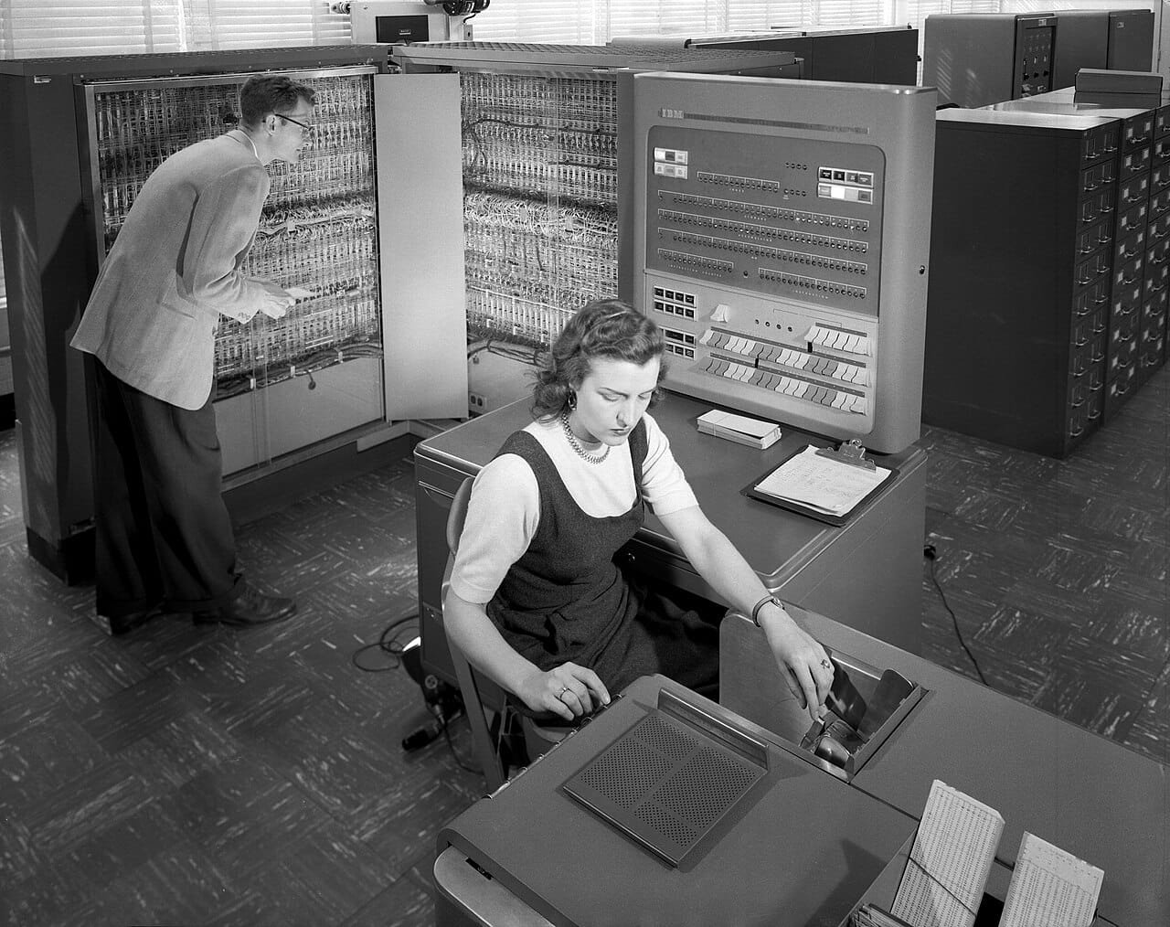 An early data processing installation. The first programs were written directly in machine or assembly code, and the labour involved is what motivated higher-level languages.