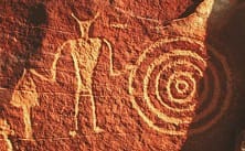 Petroglyphs pecked into a desert surface. Removing the darkened outer layer of a rock exposes lighter stone beneath, and the contrast fades slowly as the new surface weathers.