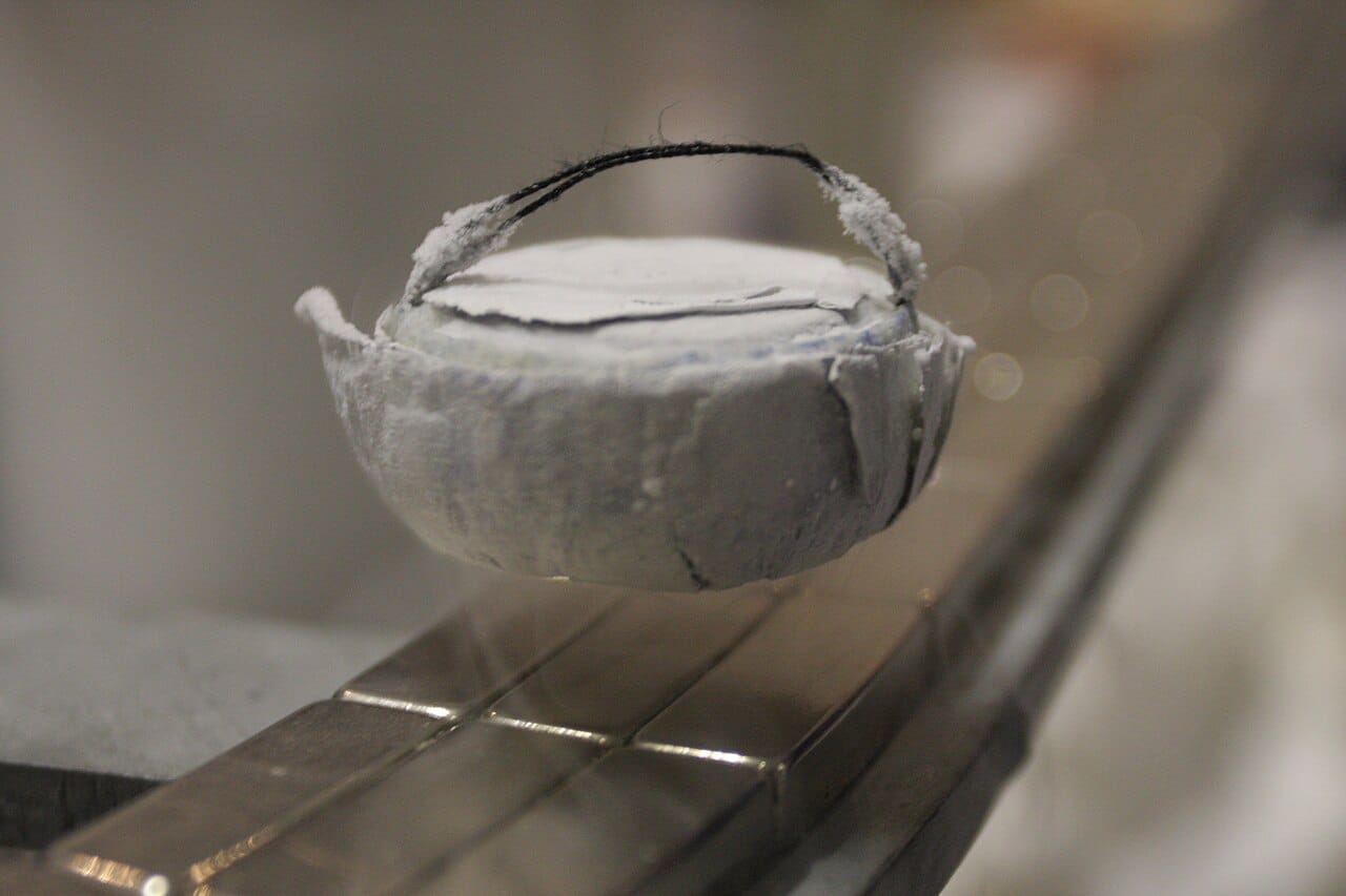 A superconductor levitating above a magnet while cooled by liquid nitrogen. The expulsion of magnetic field, rather than merely low resistance, is the property that identifies a true superconductor.