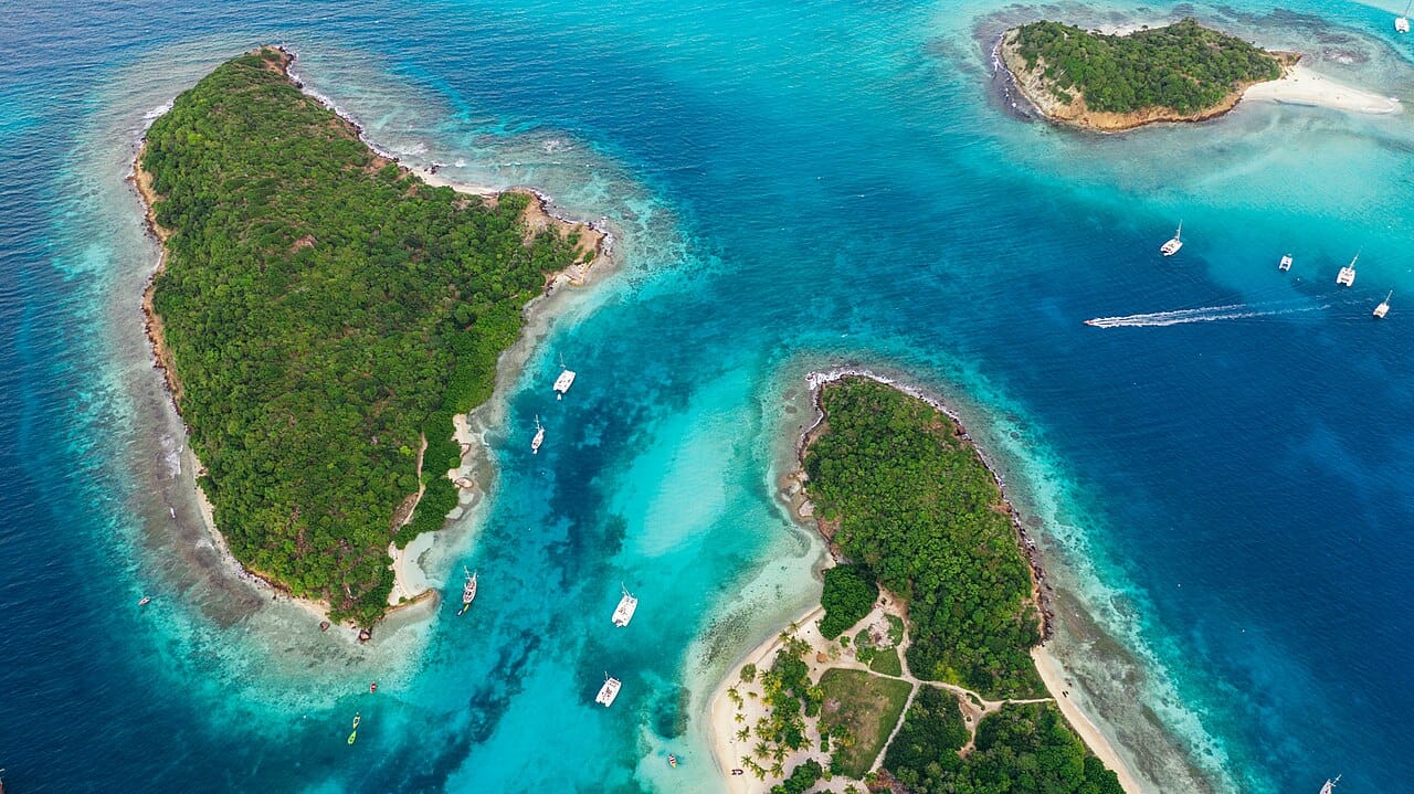 The Tobago Cays, uninhabited islets inside a horseshoe reef. The Grenadines are among the best-known sailing waters in the world, and Hurricane Beryl devastated the southern islands in July 2024.