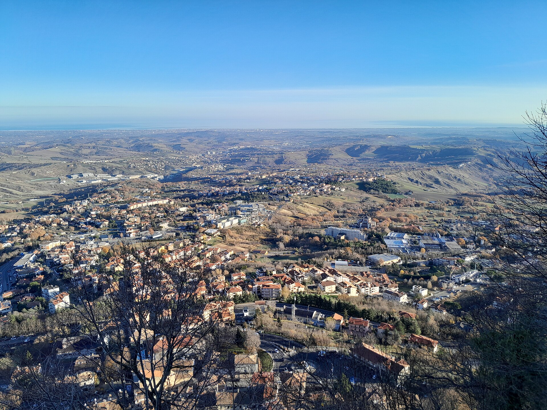 A view from the City of San Marino, the capital clinging to the summit of Monte Titano. The little republic of steep streets and medieval stone lives on tourism, finance, and the pride of its unbroken independence.