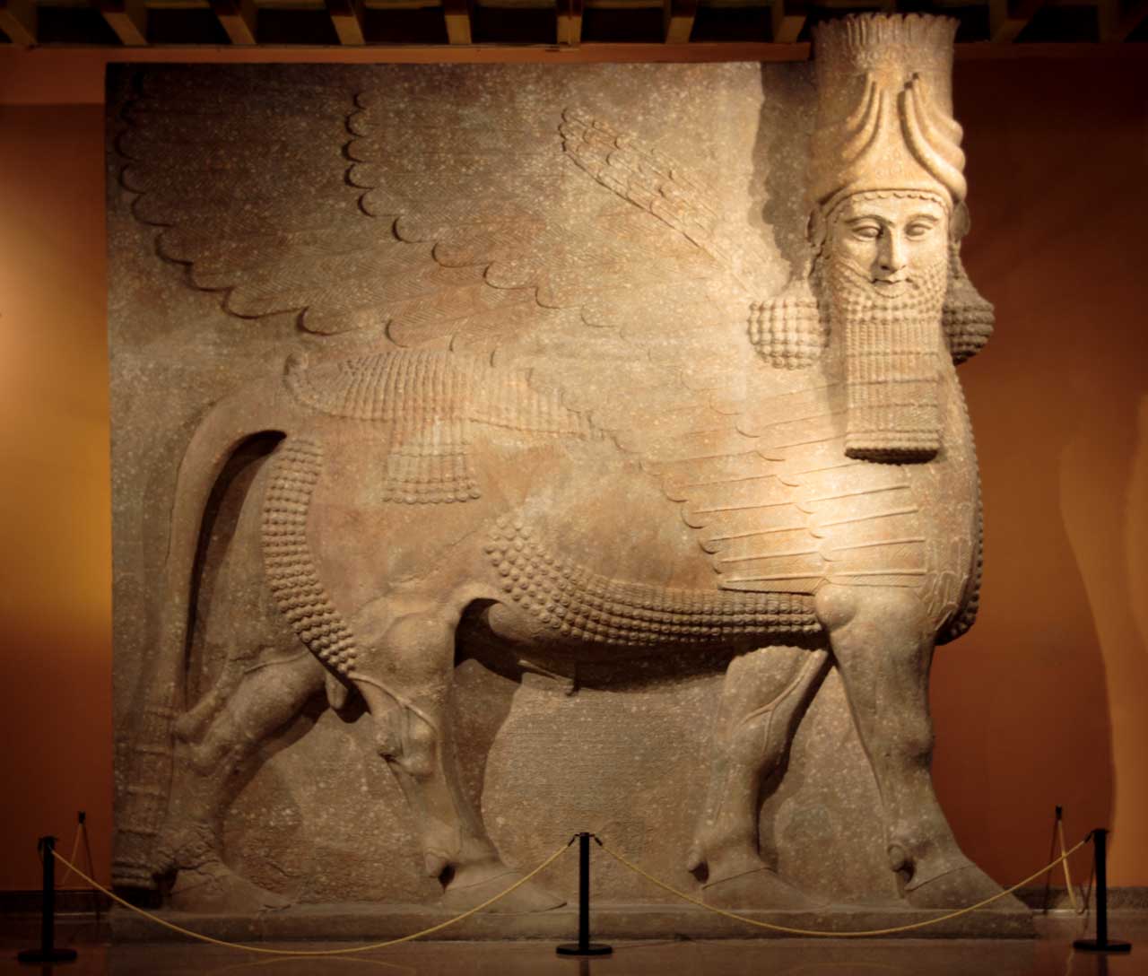 A colossal Assyrian guardian figure. Working stone at this scale required organised labour and a tradition of technique, and the material determined the frontal, blocky treatment.