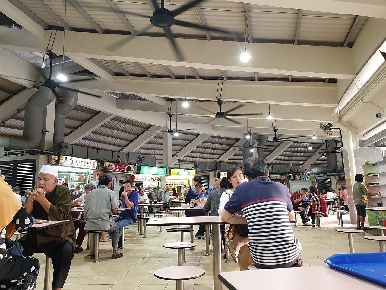 A hawker centre in Singapore. These open-air stall complexes are where most of the country eats, and hawker culture was inscribed on the UNESCO intangible cultural heritage list in 2020 as a shared space cutting across every community.