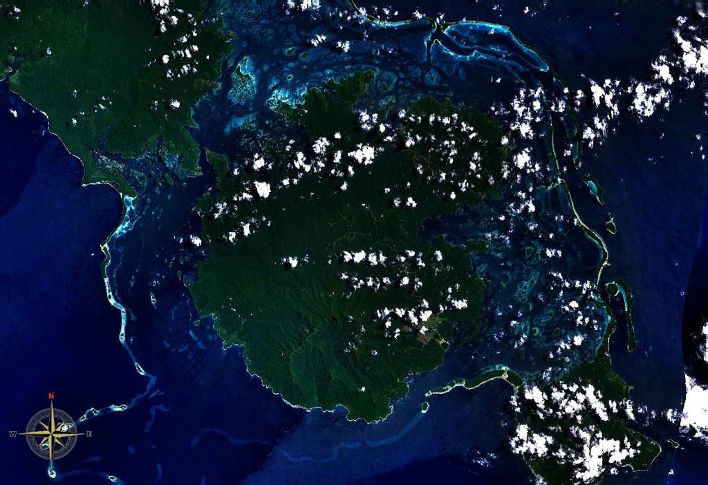 An island and its encircling reefs in the Solomons, seen from space. The archipelago of nearly a thousand islands, ringed by coral lagoons such as the famous Marovo, is one of the most beautiful and least developed corners of the Pacific.