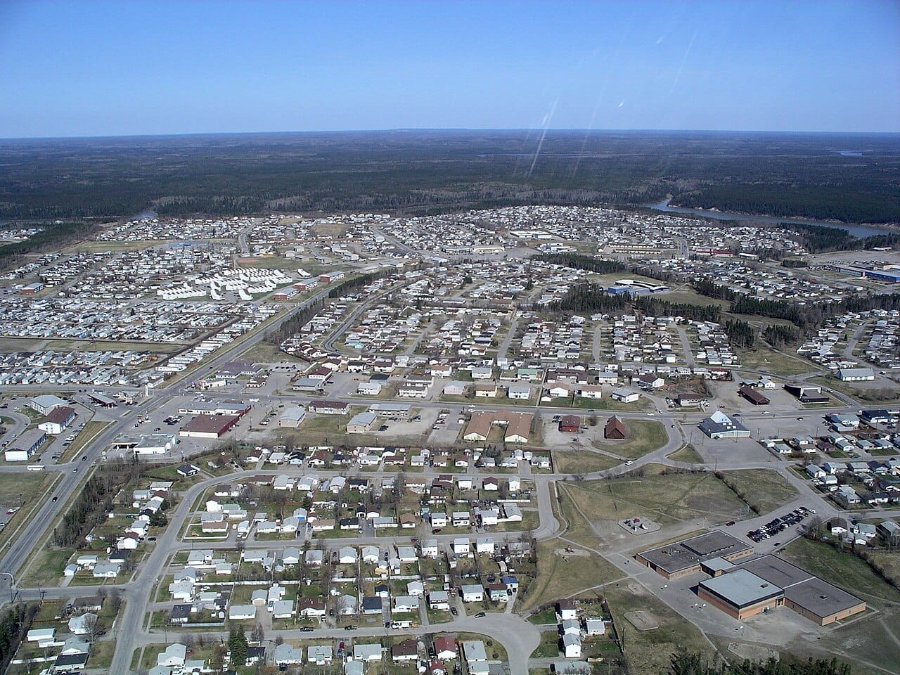 Thompson from the air. The city sits in continuous boreal forest, and the surrounding country is lake, muskeg and rock rather than farmland.