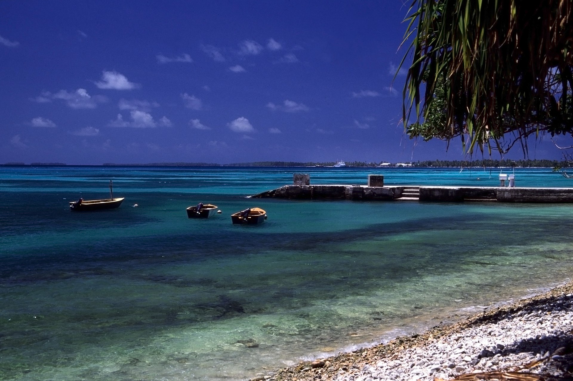 A jetty and beach on Funafuti atoll, the main island of Tuvalu. Most of the nation's small population lives on this thin ribbon of coral, the site of the capital, the harbour, and the country's only airfield.