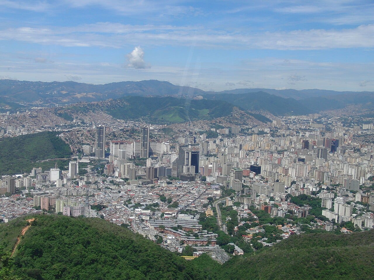 Caracas, the capital of Venezuela, spread through a valley beneath the green wall of the Avila mountain. Home to much of the nation's people and power, the city embodies both the oil wealth of the past and the hardships of the present.