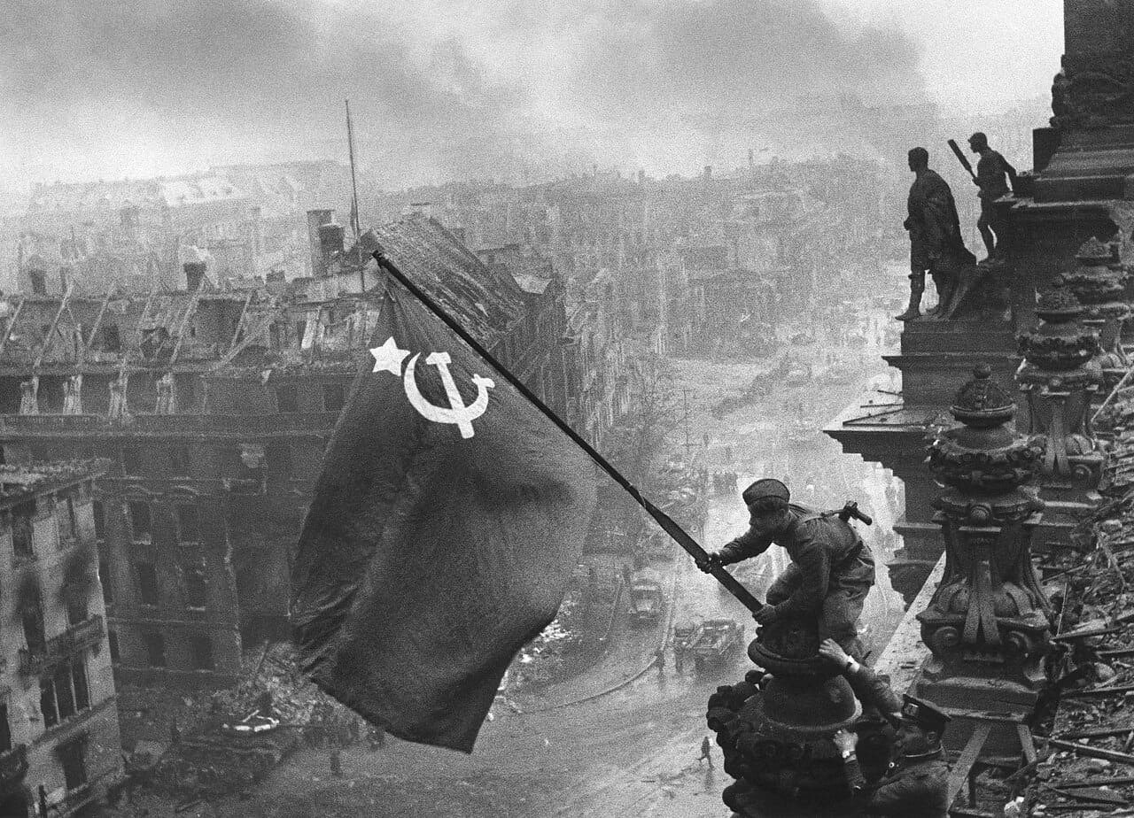 A Soviet soldier raising the flag over the Reichstag in Berlin, May 1945, an enduring image of Germany's defeat.