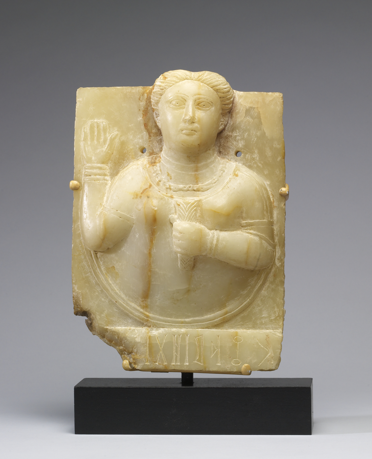 A carved gravestone of a woman holding a stylised sheaf of wheat, from the ancient Sabaean kingdom. Such finely worked stones reflect the wealth and artistry of the incense kingdoms of ancient Yemen.